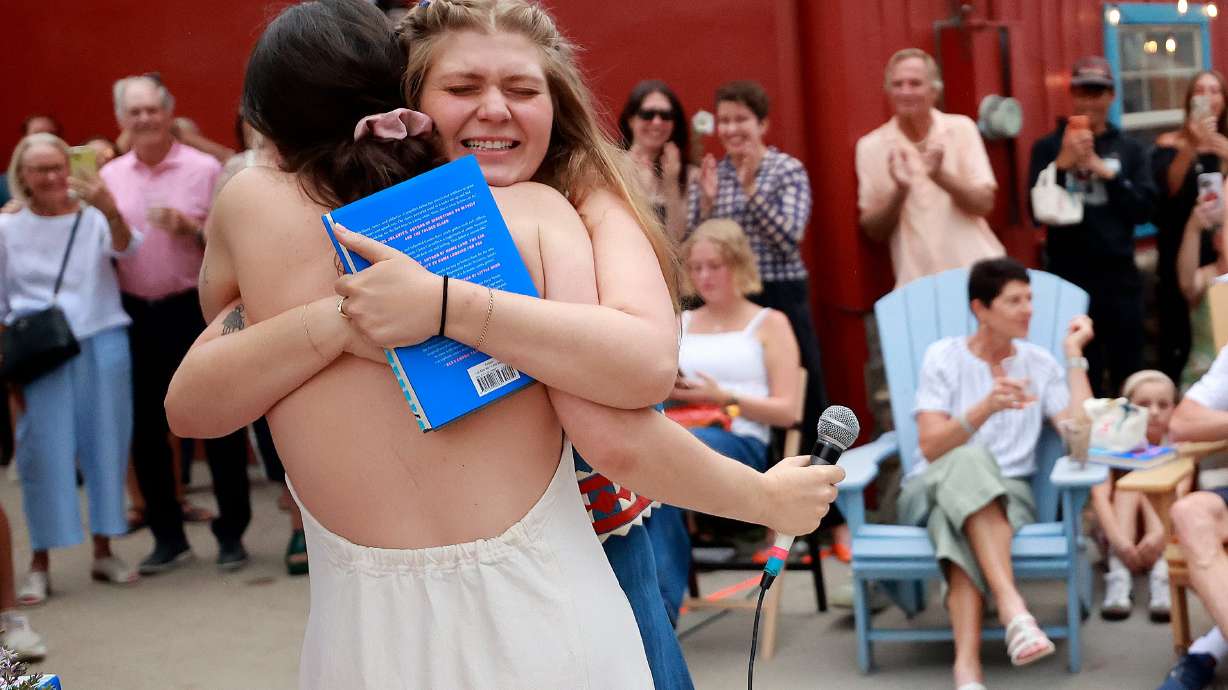 Claire Carusillo, right, hugs her friend Maria Yagoda after Yagoda introduced Carusillo at a book release event for Carusillo’s novel “The Responsible Party,” at Storyboard book, skate and coffee shop in Midway on Aug. 10.