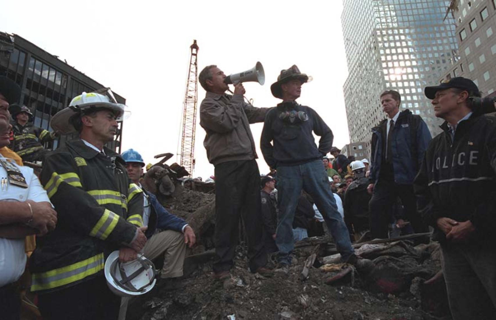 Standing atop rubble with retired New York City firefighter Bob Beckwith, President George W. Bush addresses about 400 police, firemen and rescue workers by bullhorn at the site of the collapsed World Trade Center in New York City. September 14, 2001.