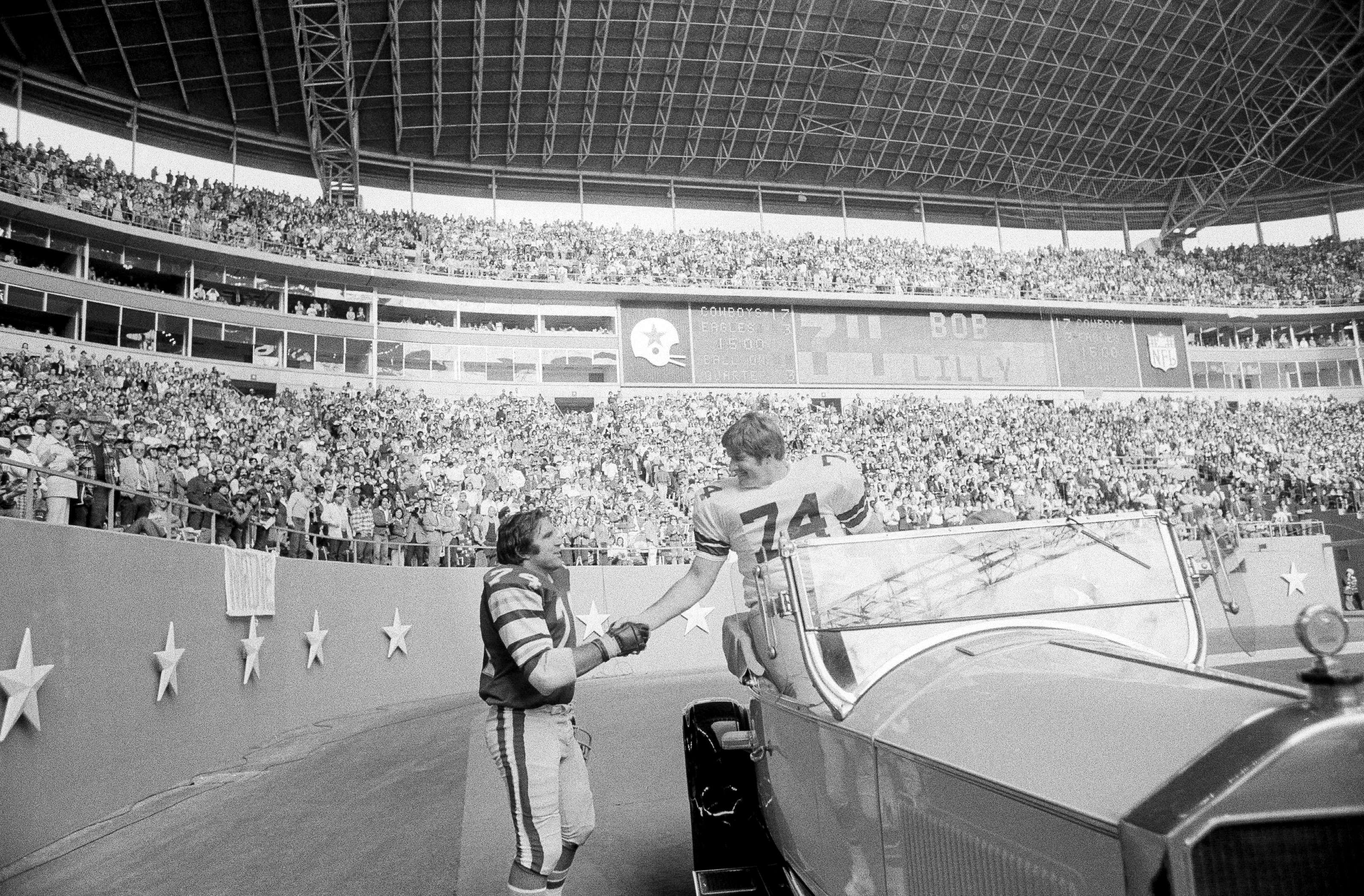 FILE - Philadelphia Eagles guard John Niland (74), right, shakes hands with retired Dallas Cowboys tackle Bob Lilly (74) during half-time ceremonies honoring Lilly at Texas Stadium in Irving, Nov. 23, 1975. Niland and Lilly were teammates the previous year. 