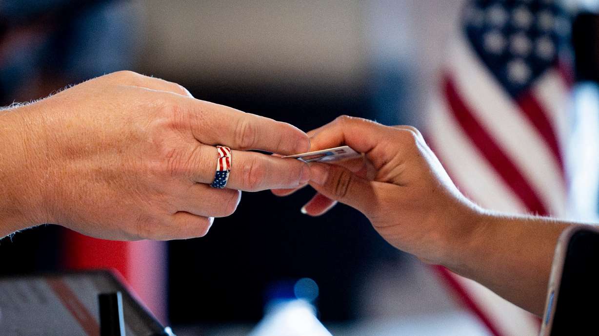 A poll worker hands a voter back their driver's license as part of Utah’s primary election at CenterPoint Church in Orem on June 23.