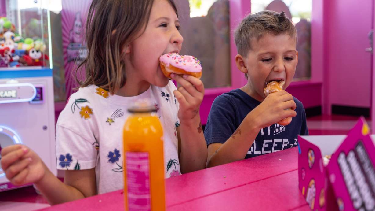 Brooklin Giles, 8, and her brother Liam Giles, 6, chomp down on doughnuts at the new Pinkbox Doughnuts located at 10235 State St. in Sandy on Sunday.