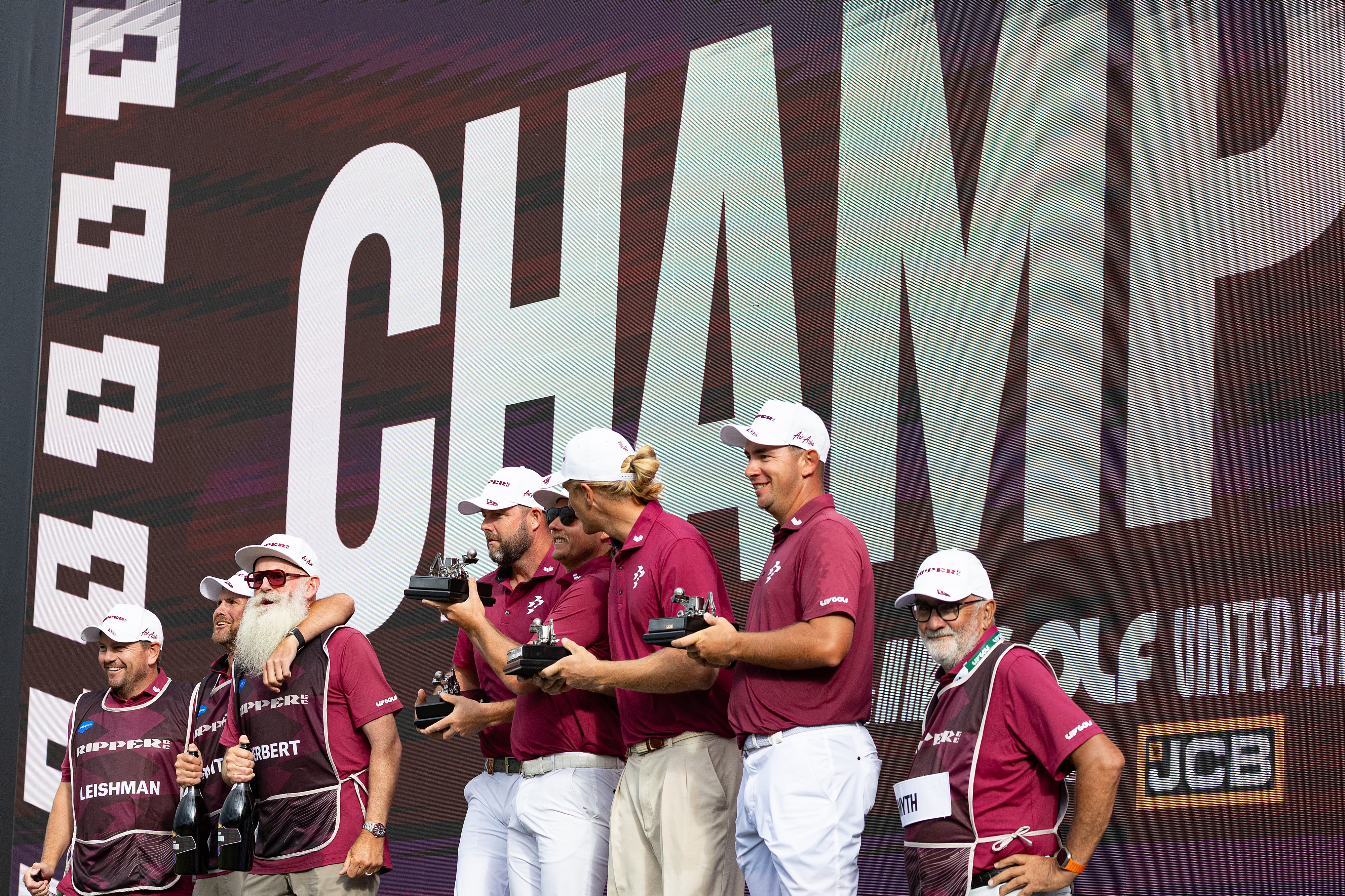 Team champions captain Cameron Smith, Marc Leishman, Lucas Herbert and Travis Smyth, of Ripper GC, and their caddies celebrate onstage after their first-place win following the final round of the LIV Golf United Kingdom golf tournament Sunday, July 26, 2026, in Rocester, England. 
