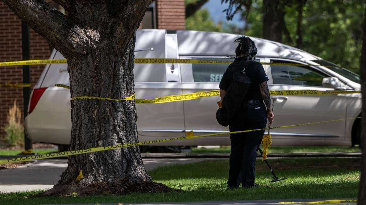 A member of the forensics unit uses a metal detector to search for evidence as police investigate a shooting that occurred in Kearns during a funeral on Monday.