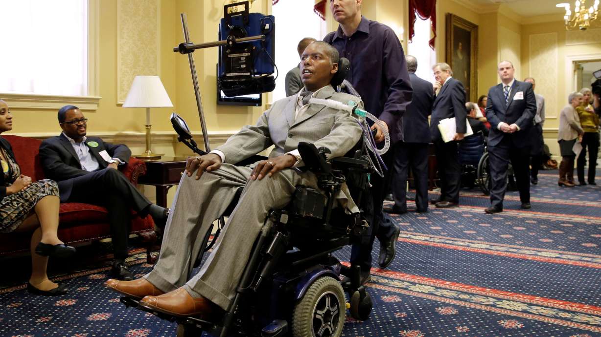 FILE - Former Baltimore Ravens NFL football player O.J. Brigance, center, current senior advisor to player development, is pushed by a nurse outside of a committee room in Annapolis, Md., March 10, 2015, after testifying to Maryland lawmakers against a right-to-die bill.