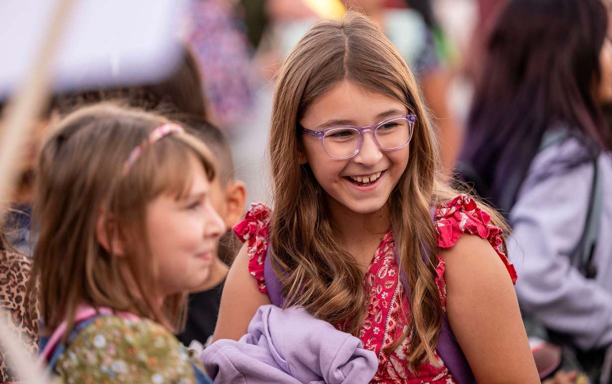 Emily Olson laughs and smiles as she talks with friends as Sandy Elementary welcomes its students back to school with a celebratory atmosphere and a red-carpet walk on Monday.