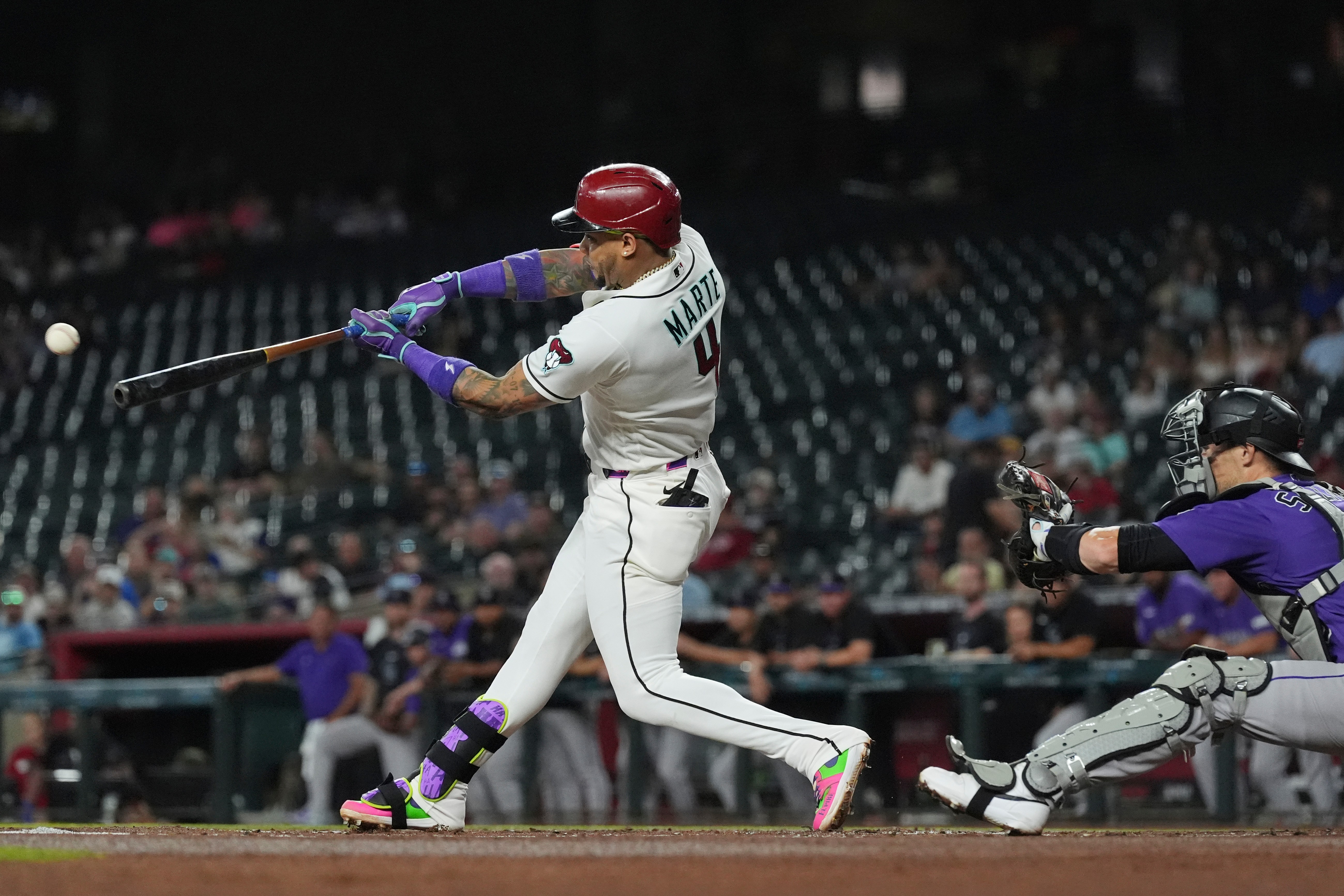 Arizona Diamondbacks' Ketel Marte (4) hits a run-scoring single as Colorado Rockies catcher Brett Sullivan reaches for the ball during the first inning of a baseball game, Wednesday, Aug. 12, 2026, in Phoenix. 