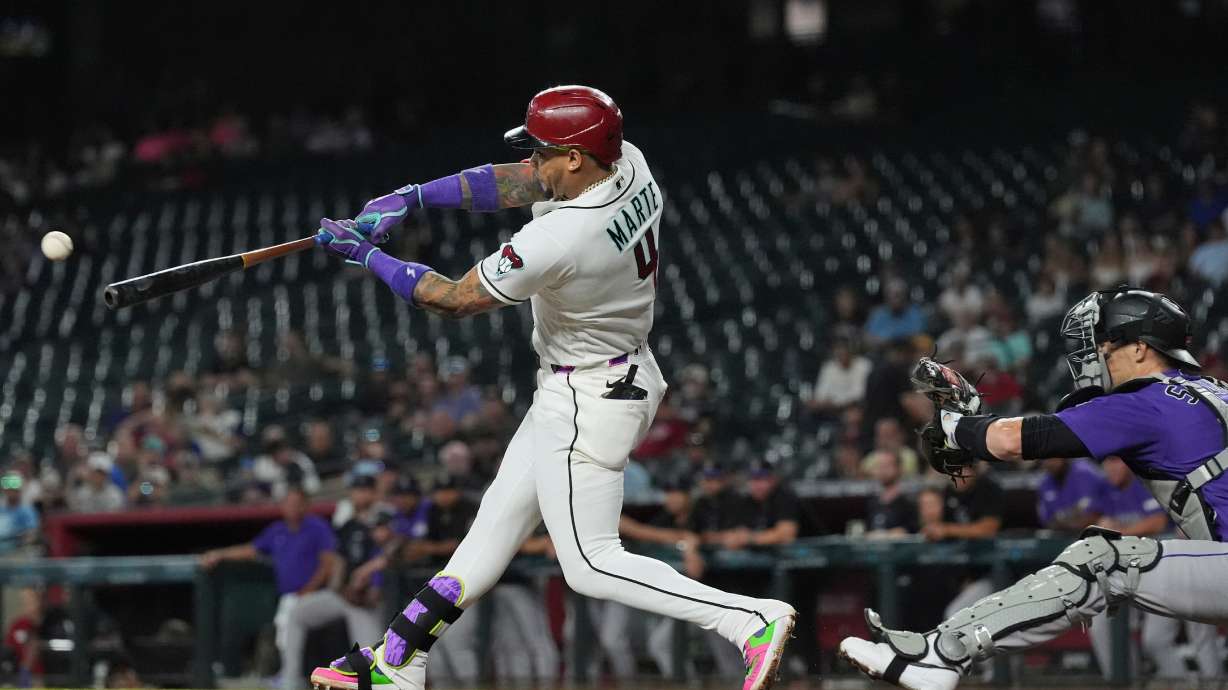 Arizona Diamondbacks' Ketel Marte (4) hits a run-scoring single as Colorado Rockies catcher Brett Sullivan reaches for the ball during the first inning of a baseball game, Wednesday, Aug. 12, 2026, in Phoenix.