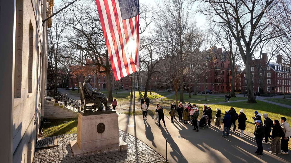 People take photos near a John Harvard statue on the Harvard University campus, Jan. 2, 2024, in Cambridge, Mass. The Department of Defense has ordered 30 universities, including Harvard, to audit their partnerships with mostly Chinese universities and military training institutions.