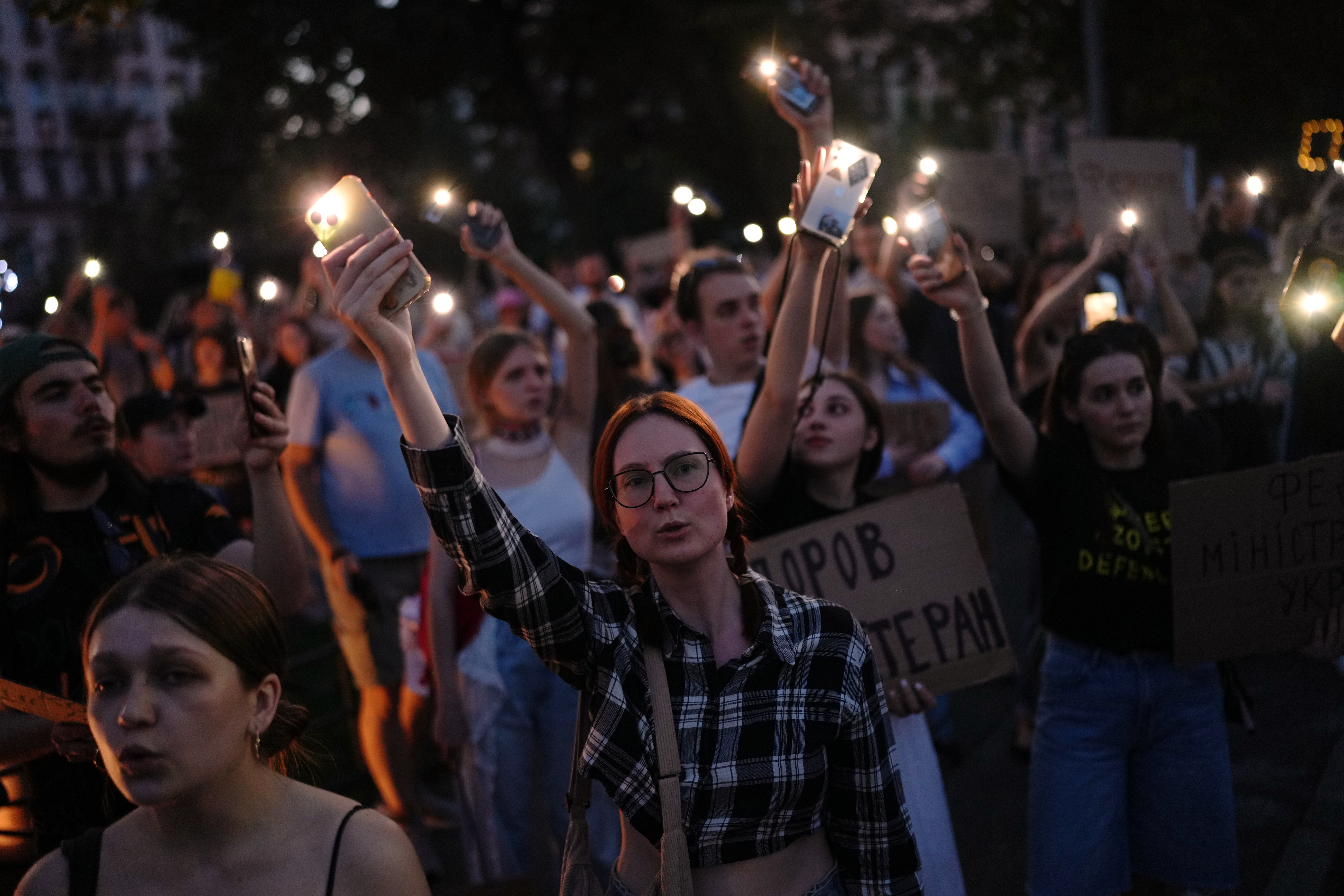 People sing and hold up their cell phone flashlights during a rally to protest the dismissal of Mykhailo Fedorov as Ukraine's Defense Minister in Kyiv, late Sunday. Fedorov made a call for national elections amid the war with Russia on Wednesday.