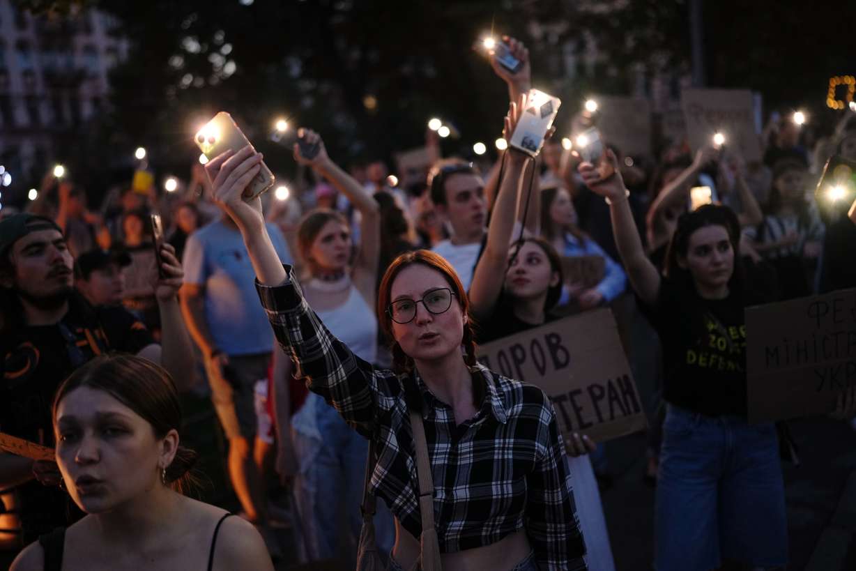 People sing and hold up their cell phone flashlights during a rally to protest the dismissal of Mykhailo Fedorov as Ukraine's Defense Minister in Kyiv, late Sunday. Fedorov made a call for national elections amid the war with Russia on Wednesday.