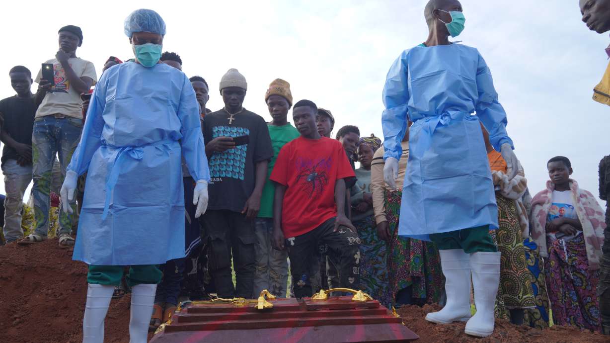 People dressed in protective gear prepare to lower into a grave the coffin containing the remains of 3-year-old Mave Mercienne, who died of Ebola, in Bunia, Ituri province, eastern Congo, Tuesday. The outbreak reached 5,000 cases on Wednesday.