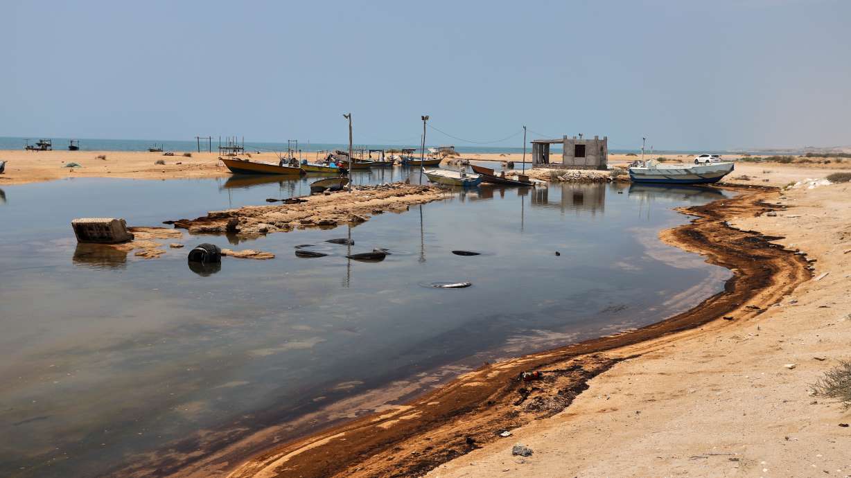 Oil residue lines the shore near fishing boats on Qeshm Island, Iran, Thursday, amid ongoing wartime attacks on vessels and infrastructure in and around the Strait of Hormuz, though the spill's source was not independently determined. The United Arab Emirates suspended trade with Iran on Wednesday after it said it had come under renewed fire.