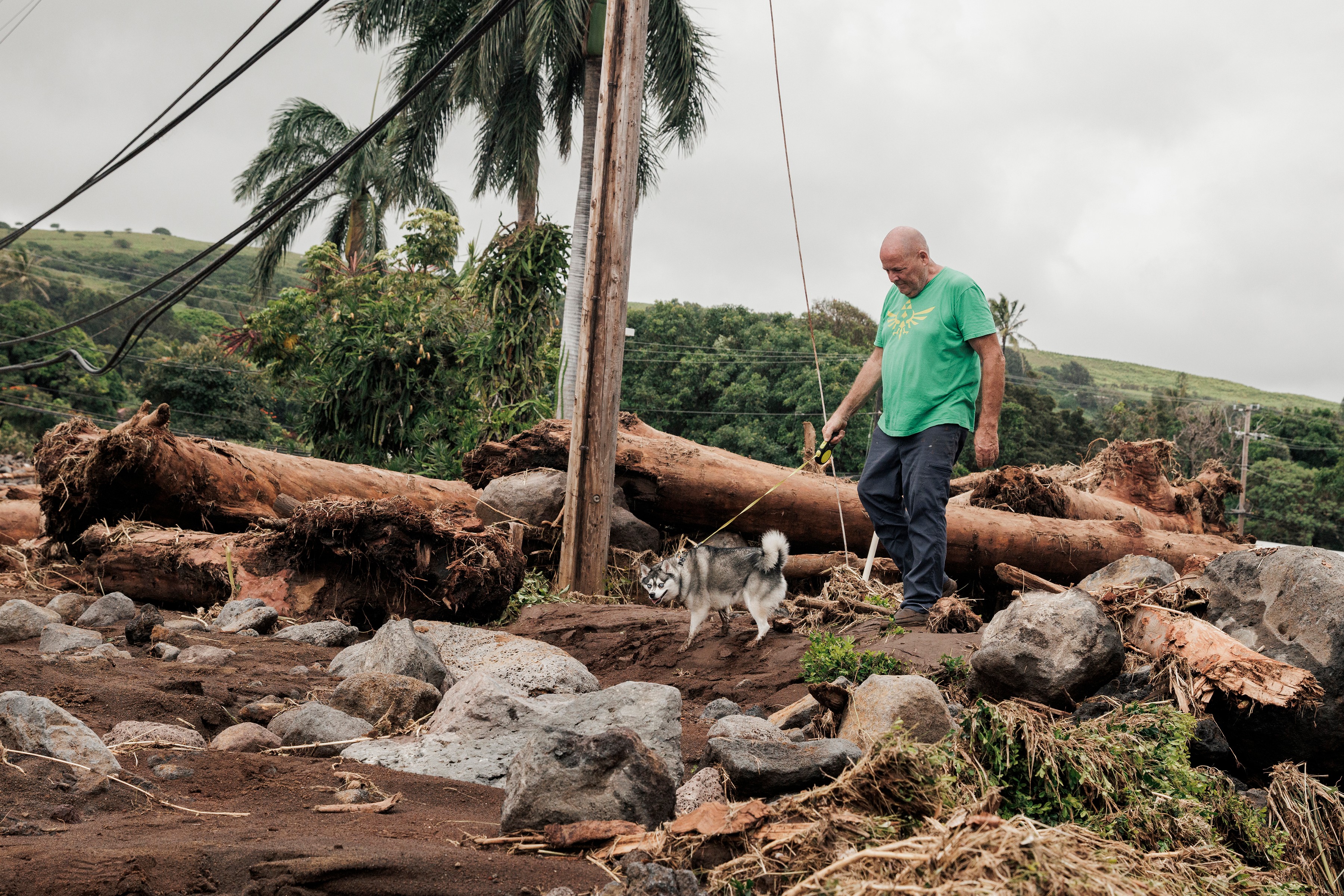 Joe Kennedy walks his dog, Cosmo, near the damaged Punalu'u Bake Shop, where his son works, after Hurricane Lala in Naalehu, Hawaii, on Monday.