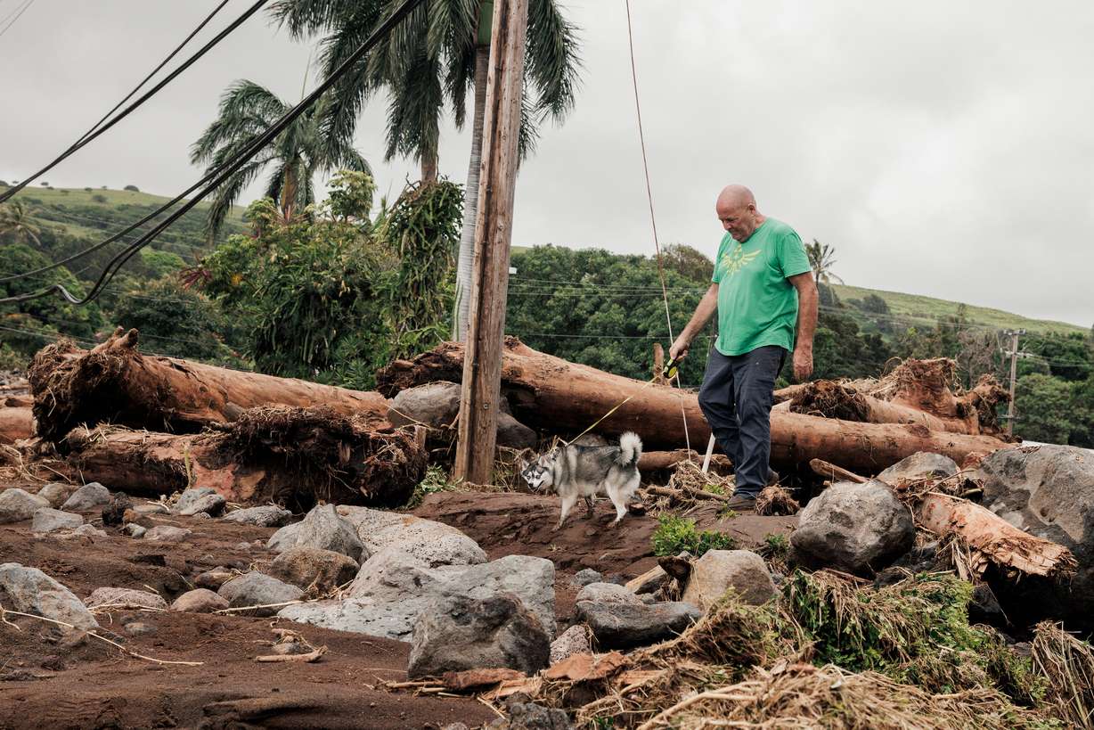 Joe Kennedy walks his dog, Cosmo, near the damaged Punalu'u Bake Shop, where his son works, after Hurricane Lala in Naalehu, Hawaii, on Monday.