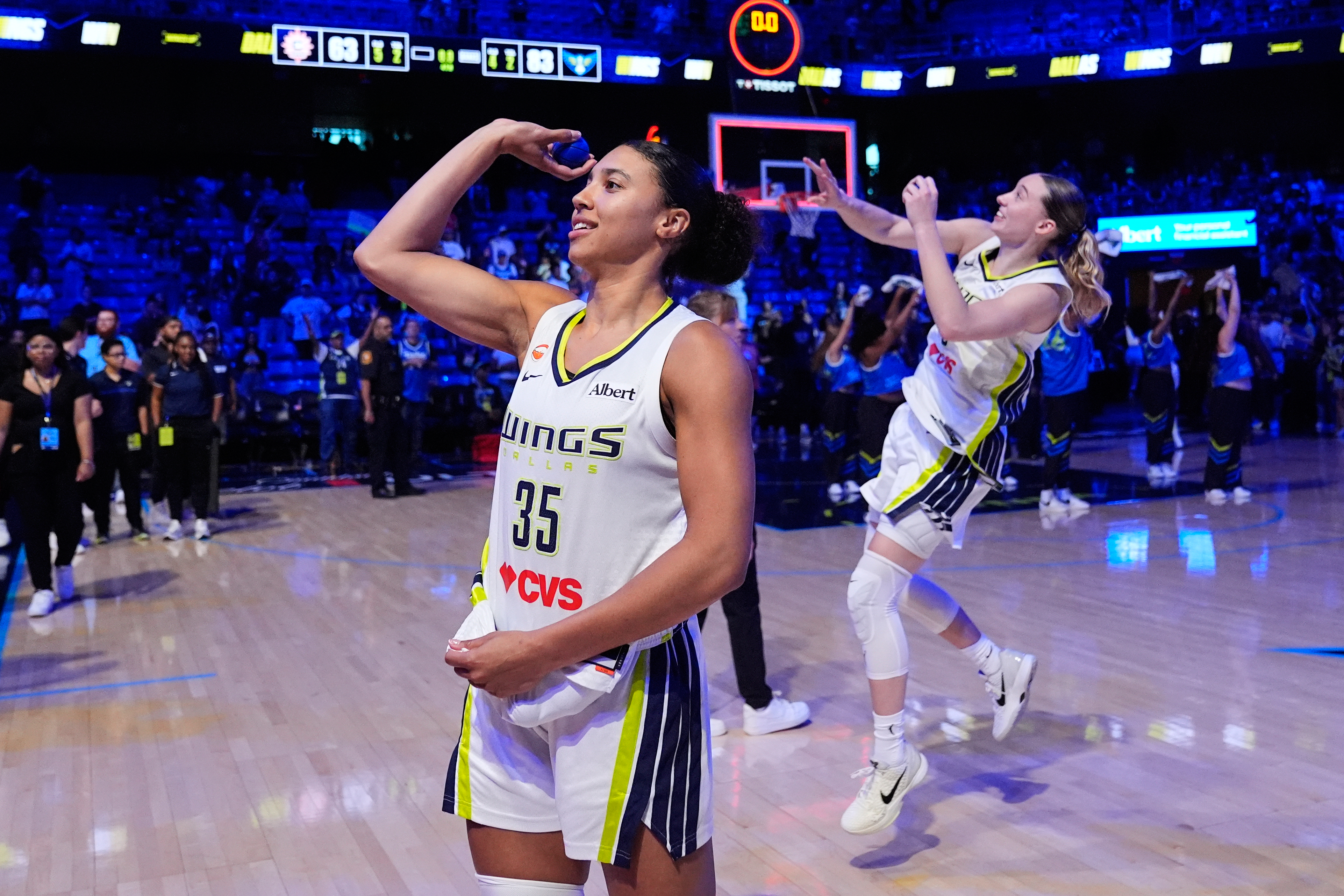 Dallas Wings guard Azzi Fudd (35) and Paige Bueckers, rear, toss keepsakes to fans after the team's win in a WNBA basketball game against the Connecticut Sun in Arlington, Texas, Sunday, Aug. 2, 2026. 