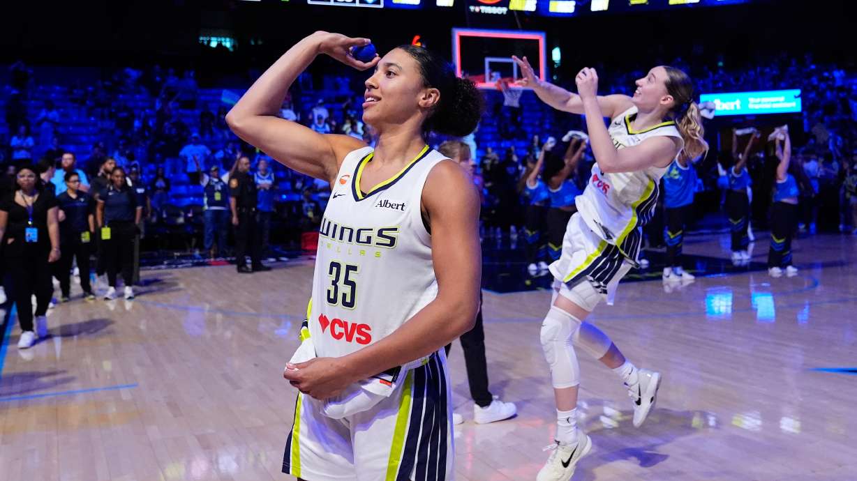 Dallas Wings guard Azzi Fudd (35) and Paige Bueckers, rear, toss keepsakes to fans after the team's win in a WNBA basketball game against the Connecticut Sun in Arlington, Texas, Sunday, Aug. 2, 2026.