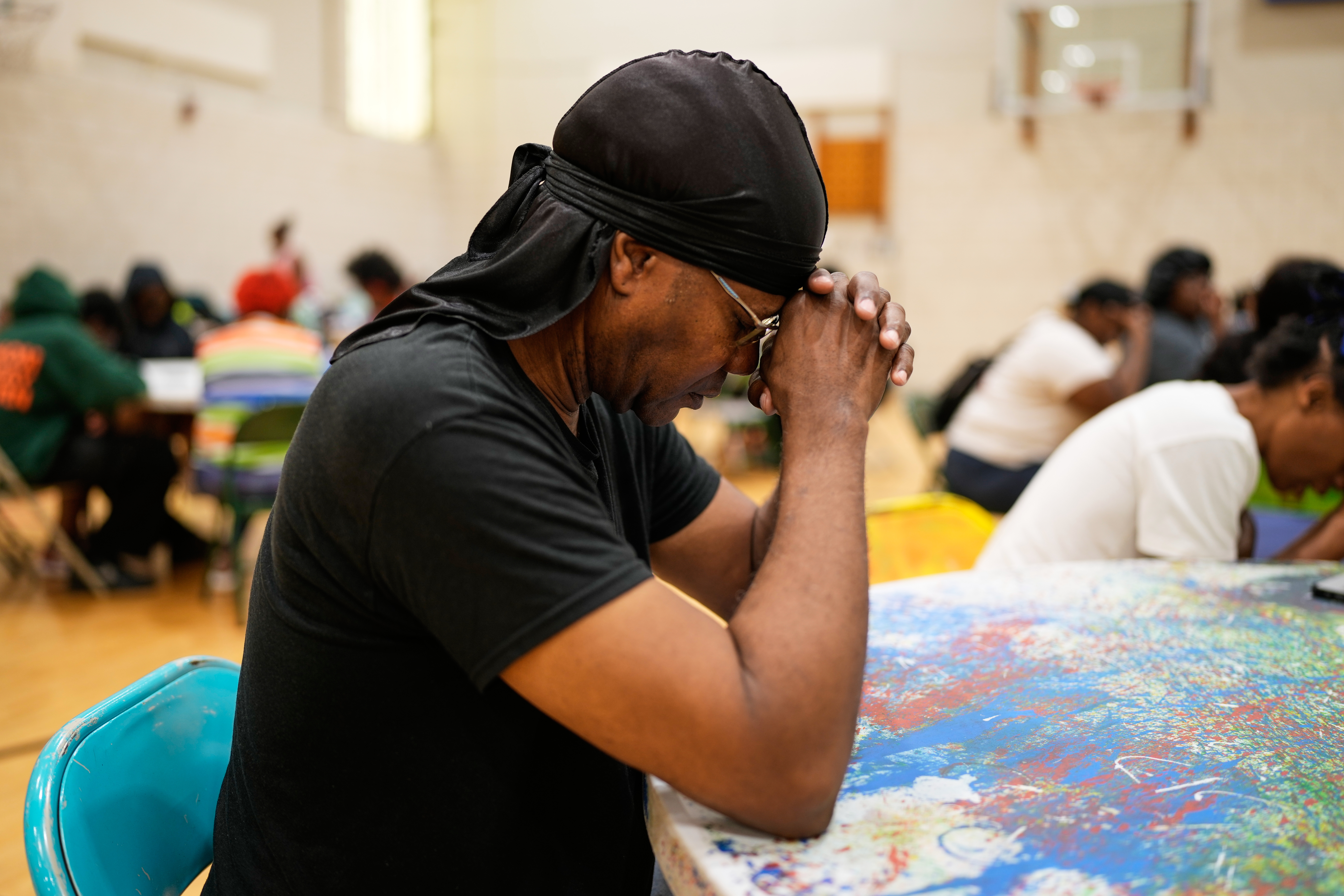 A person prays before receiving a free boxed lunch at City Life Center in Gary, Ind., Thursday, Aug. 20, 2026, more than a week after a deadly storm passed through the area. 