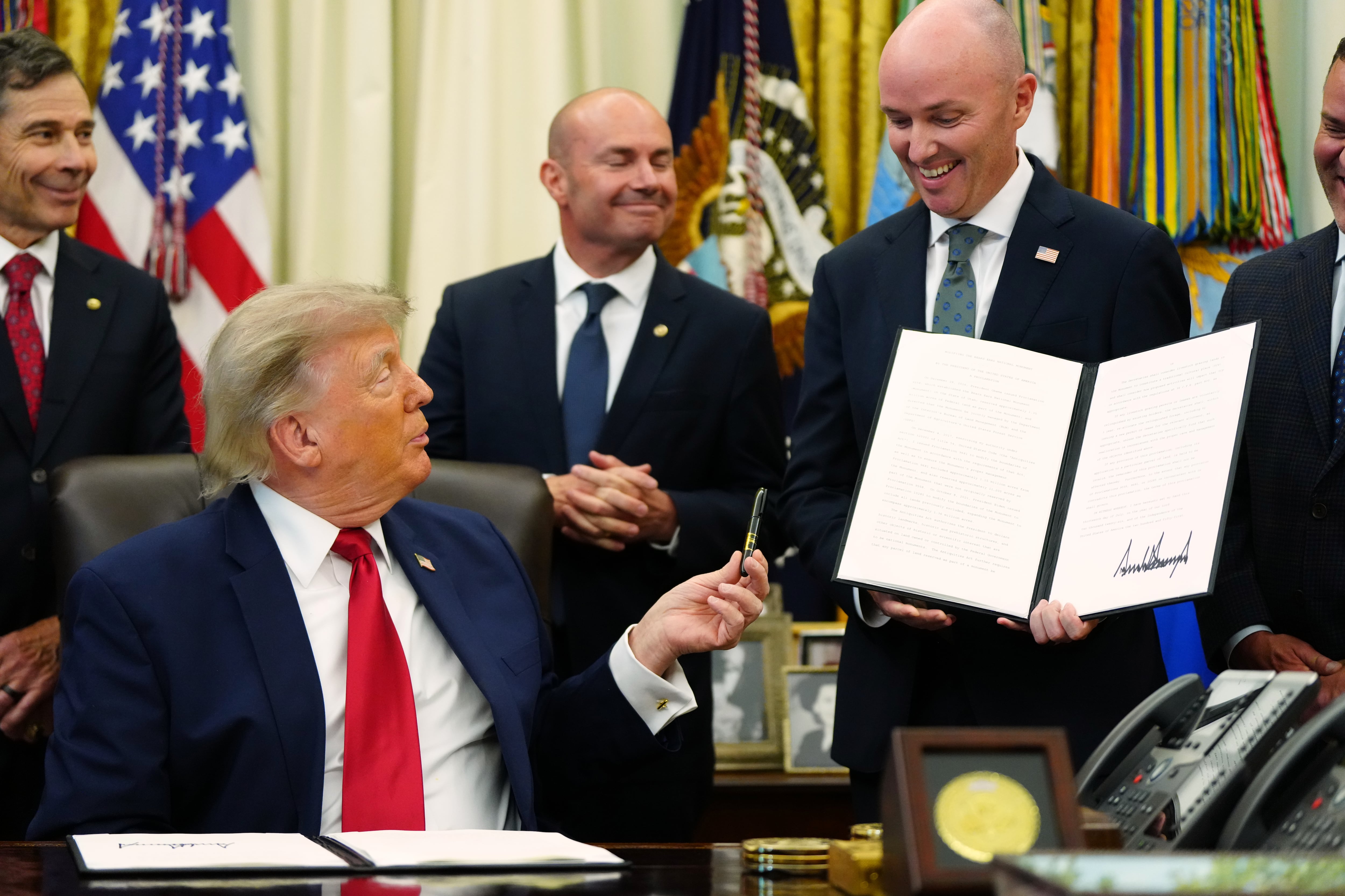 President Donald Trump hands a pen to Utah Gov. Spencer Cox after signing executive orders modifying the Grand Staircase-Escalante National Monument and the Bears Ears National Monument in the Oval Office of the White House, Monday, July 13, 2026, in Washington.