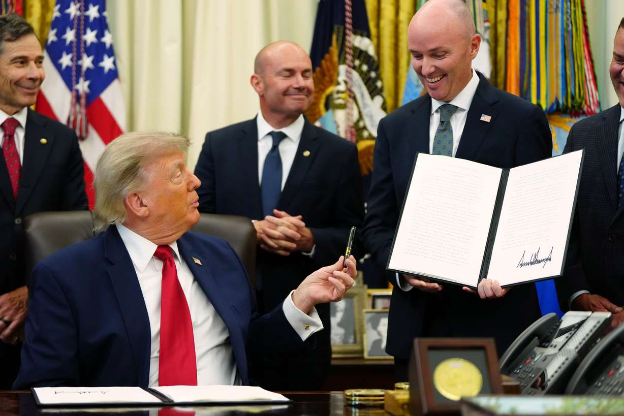 President Donald Trump hands a pen to Utah Gov. Spencer Cox after signing executive orders modifying the Grand Staircase-Escalante National Monument and the Bears Ears National Monument in the Oval Office of the White House, Monday, July 13, 2026, in Washington.