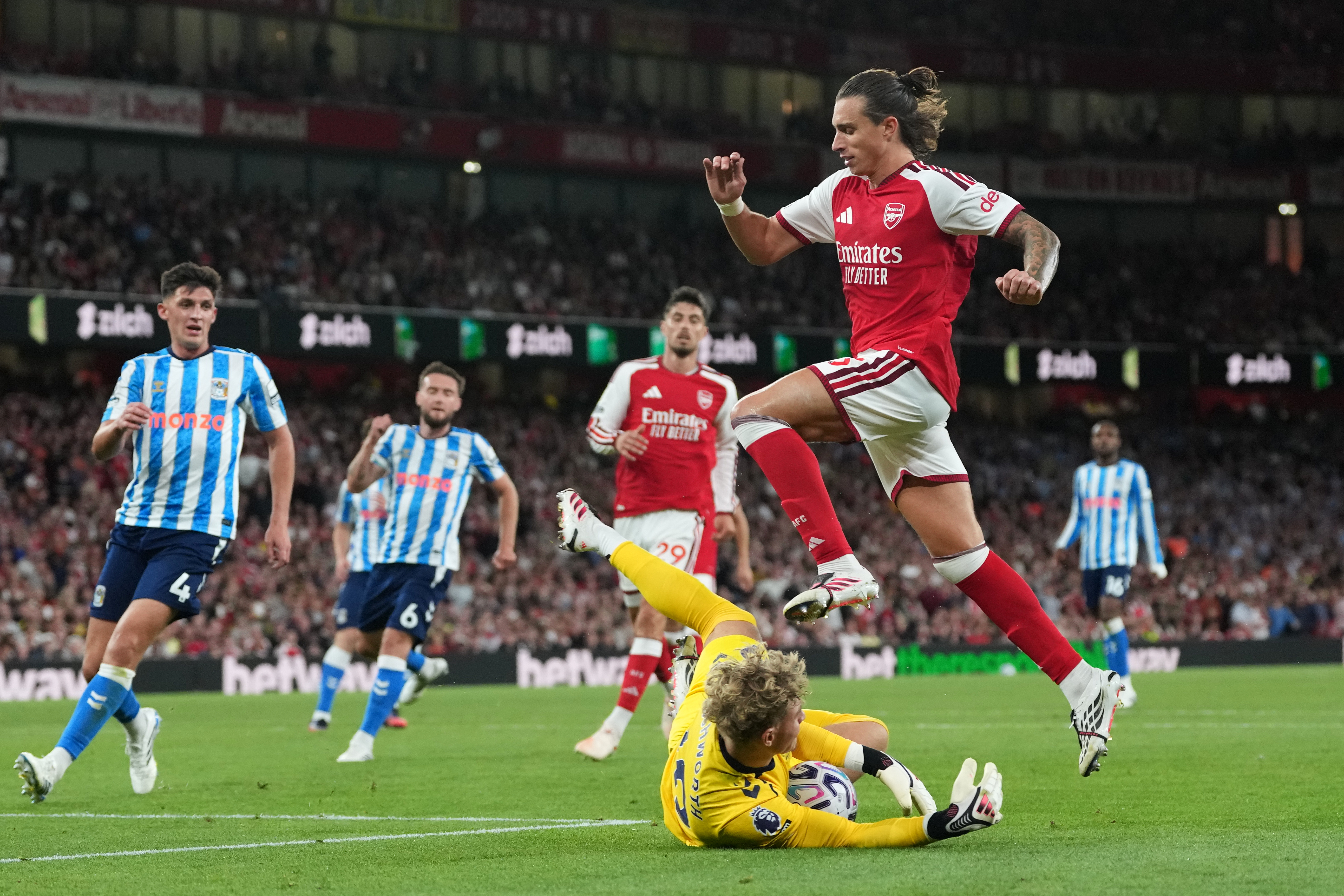 Arsenal's Riccardo Calafiori leaps over Coventry City's goalkeeper Carl Rushworth during the English Premier League soccer match between Arsenal and Coventry City in London, Friday, Aug. 21, 2026. 