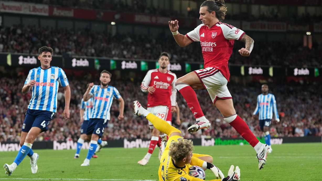 Arsenal's Riccardo Calafiori leaps over Coventry City's goalkeeper Carl Rushworth during the English Premier League soccer match between Arsenal and Coventry City in London, Friday, Aug. 21, 2026.