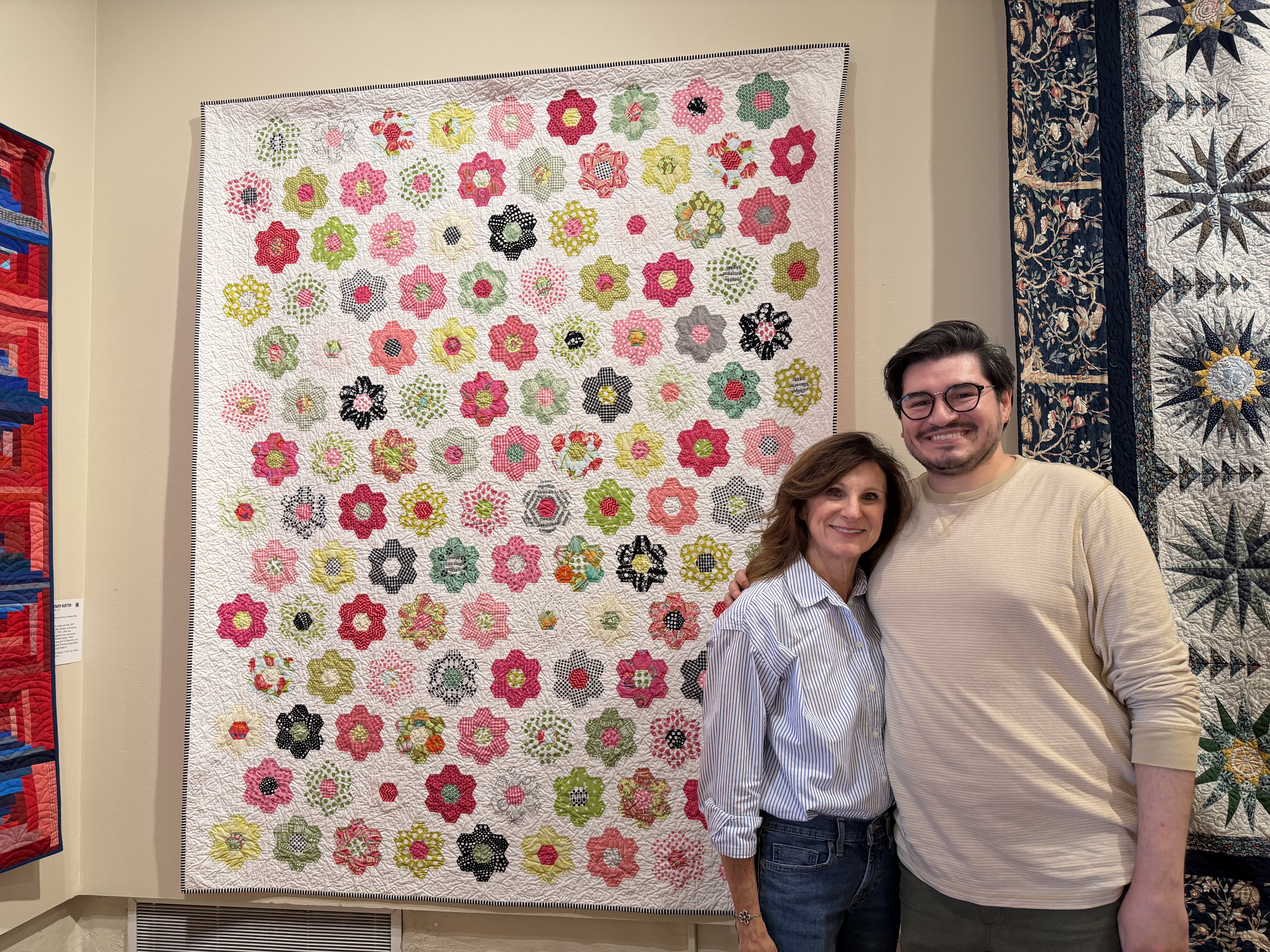 Jeri Schille and her son Colton Schille Smith stand in front of Schille's quilt titled "Eleven Years To Bloom," on Friday.