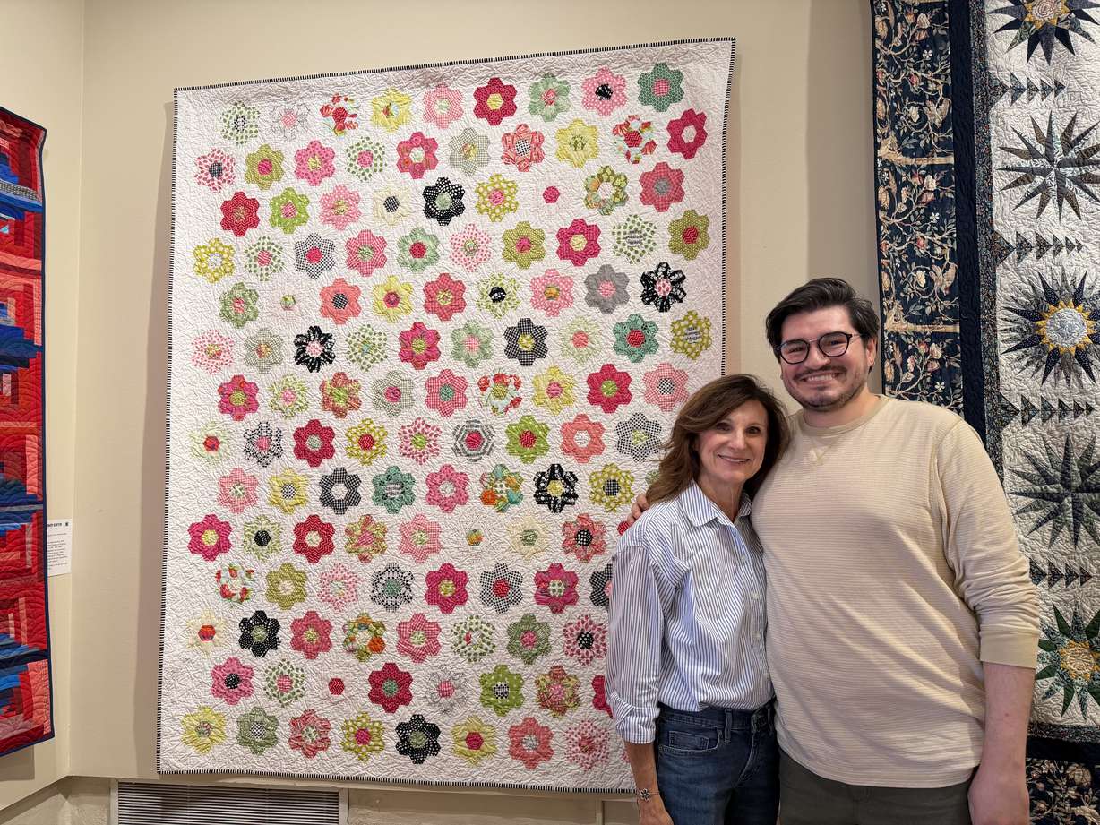 Jeri Schille and her son Colton Schille Smith stand in front of Schille's quilt titled "Eleven Years To Bloom," on Friday.