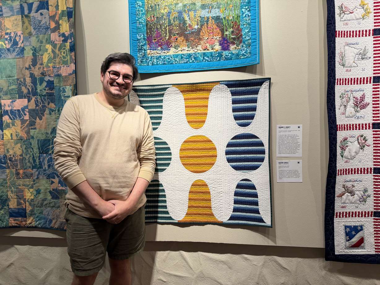 Colton Schille Smith stands in front of his quilt titled "Striped Lava Lamp," on Friday.