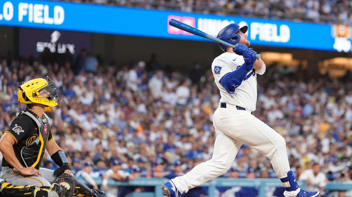 Los Angeles Dodgers' Max Muncy, right, hits a two-run home run as Pittsburgh Pirates catcher Rafael Flores Jr. watches during the first inning of a baseball game Friday, Aug. 21, 2026, in Los Angeles.