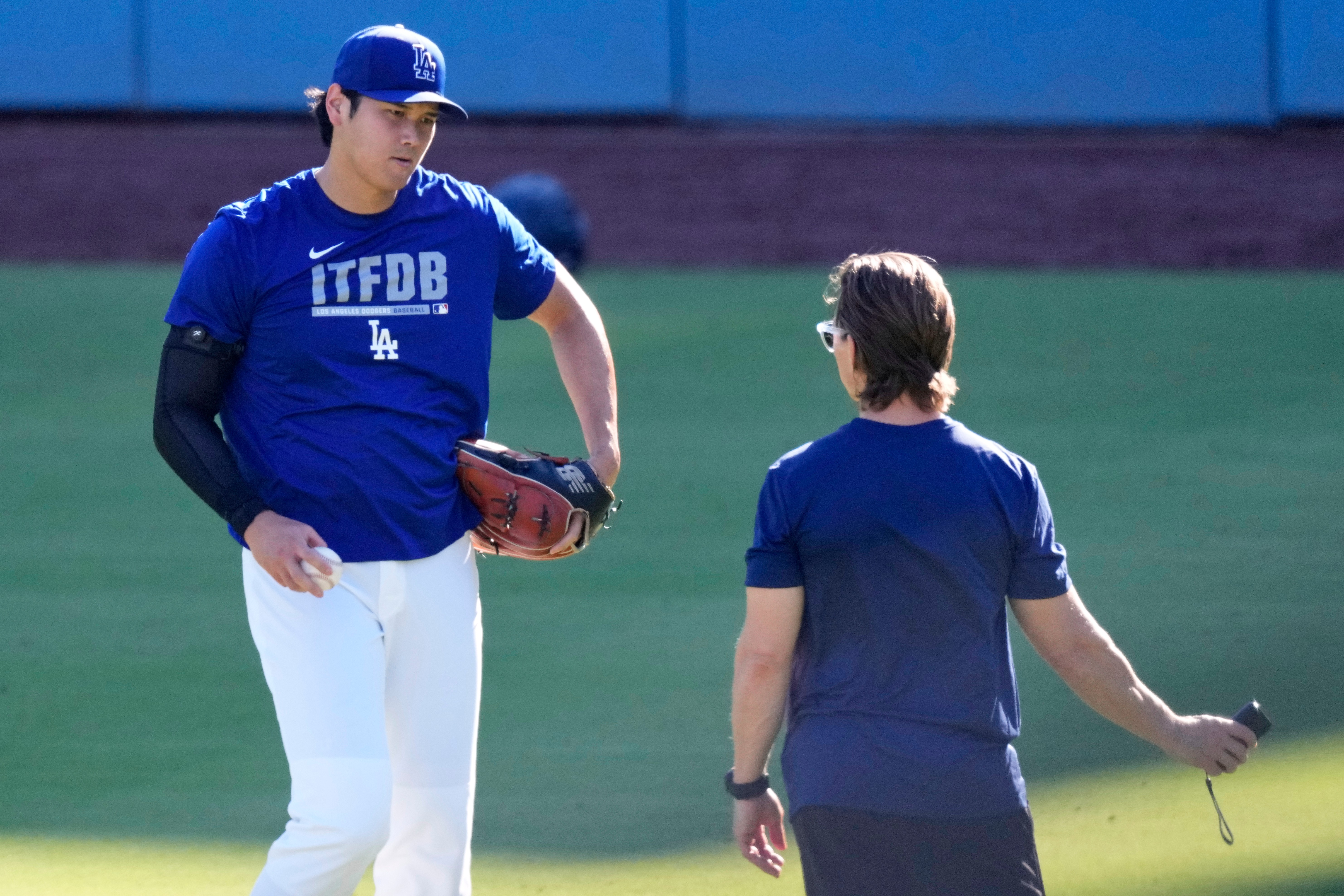 Los Angeles Dodgers' Shohei Ohtani warms up with a trainer prior to a baseball game against the Pittsburgh Pirates, Friday, Aug. 21, 2026, in Los Angeles. 
