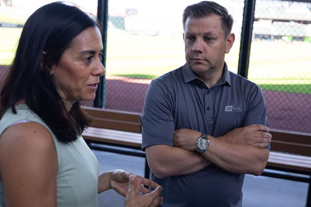 Steve Starks, the CEO of the Larry H. Miller Company and vice chair of Utah 2034, listens to Michelle Smith, the President of Miller Sports and Entertainment, speak during an interview after a presser held to announce the 2034 Olympic and Paralympic Winter Games Organizing Committee’s participation and financial support of Utah Sports Giving Day at the Ballpark at America First Square in South Jordan on Saturday.