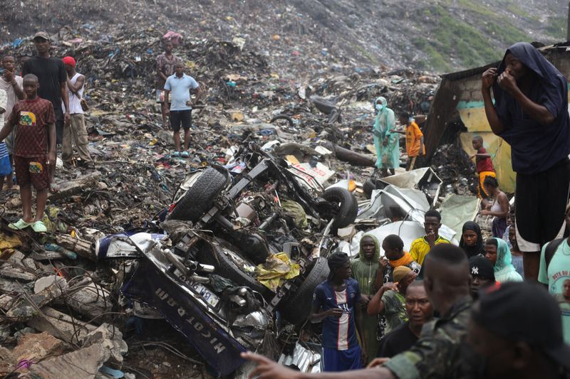 People gather at a landfill after a landslide, triggered by heavy overnight rains, killed several people in Dar es Salam in Conakry, Guinea, on Sunday.