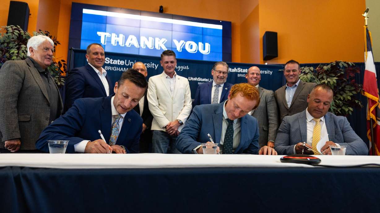 Sitting from left to right, USU President Brad Mortensen, Hi Tech Solutions President Chris Hayter and Brigham City Mayor DJ Bott sign an agreement announcing a nuclear training and research campus in Brigham City.