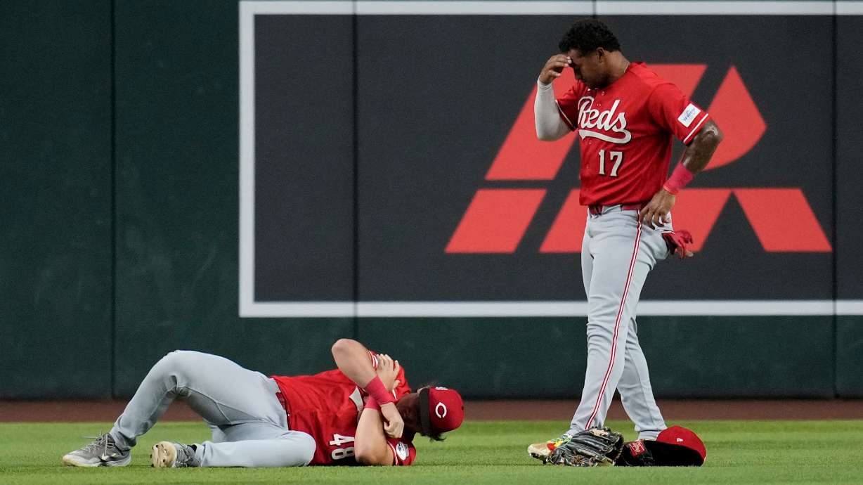 An injured Cincinnati Reds left fielder Michael Toglia (48) holds his shoulder as Reds center fielder Dane Myers (17) looks on during the first inning of a baseball game against the Arizona Diamondbacks, Friday, Aug. 21, 2026, in Phoenix.