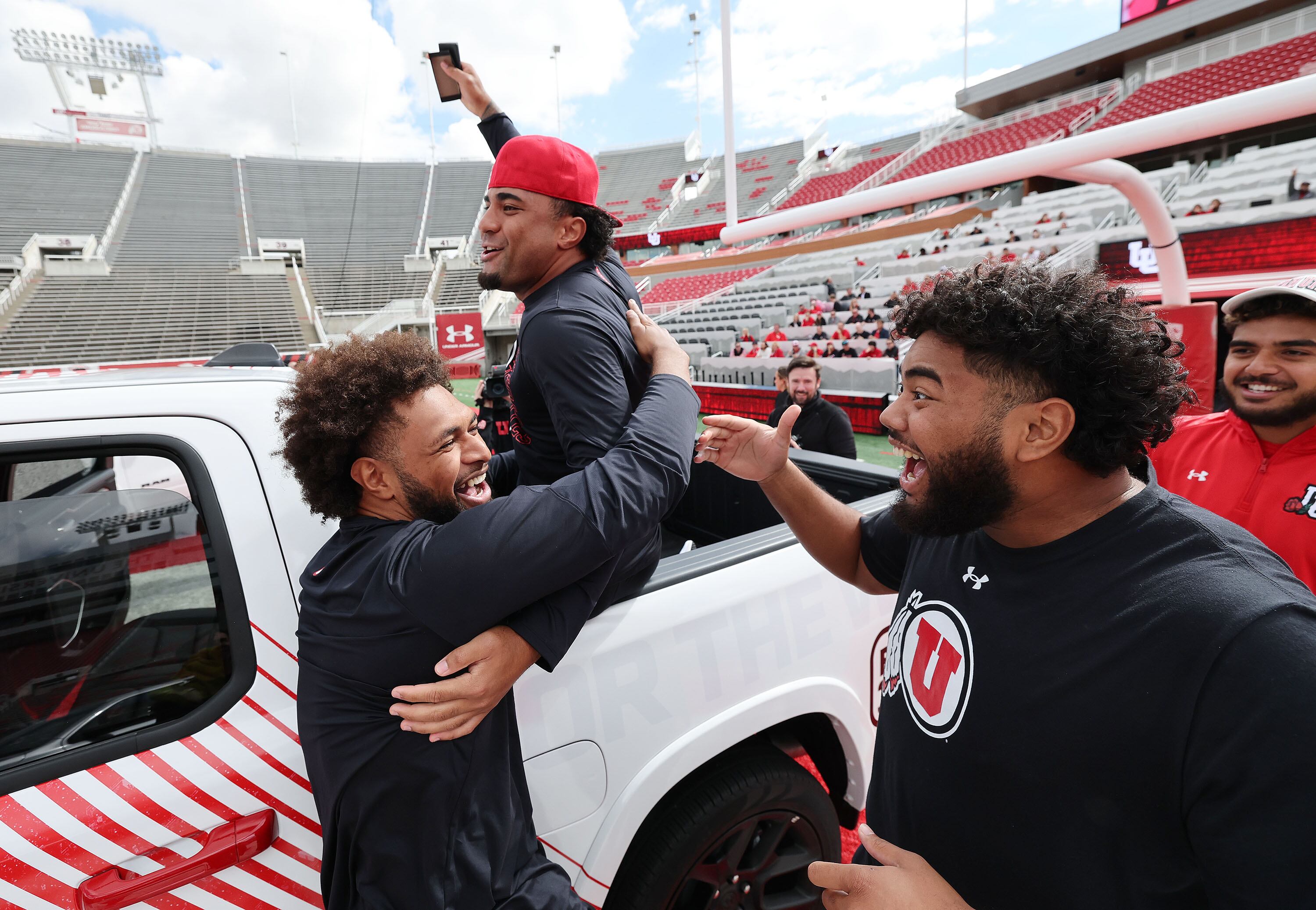 Utah Utes football scholarship players Levani Damuni, from left, Tevita Fotu and Solatoa Moea'i celebrate receiving a Dodge truck from the Crimson Collective during an NIL announcement at Rice-Eccles Stadium in Salt Lake City on Oct. 4, 2023.