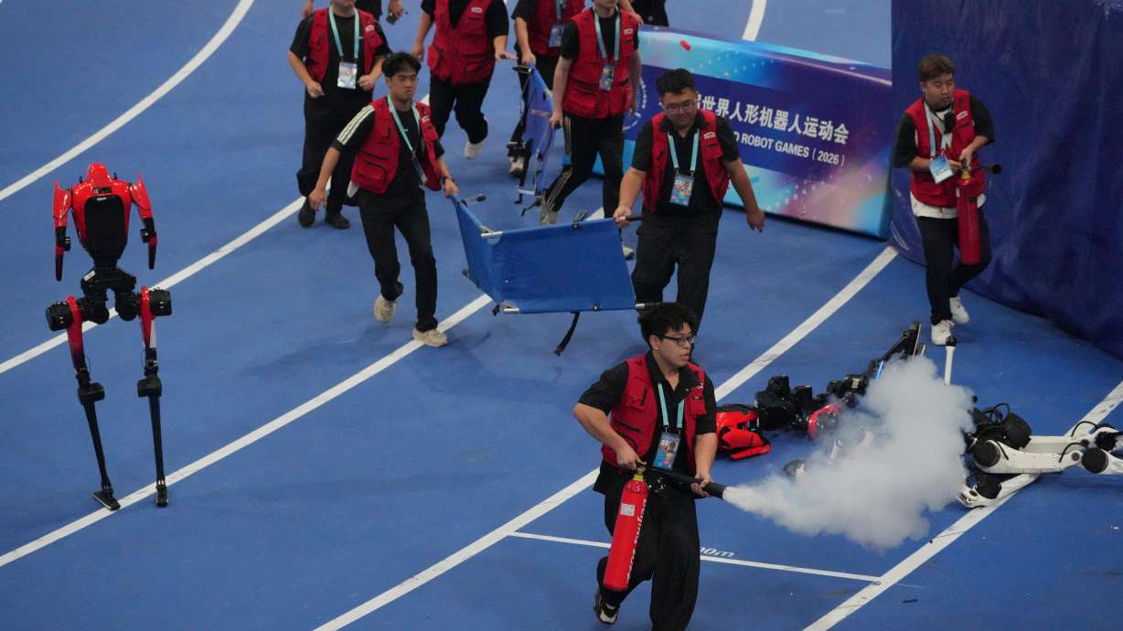 Officials extinguish a fire of a Humanoid robot after hitting the barrier at the end of the 100 meter final race during the World Humanoid Robot Games in Beijing, Wednesday, Aug. 26, 2026.