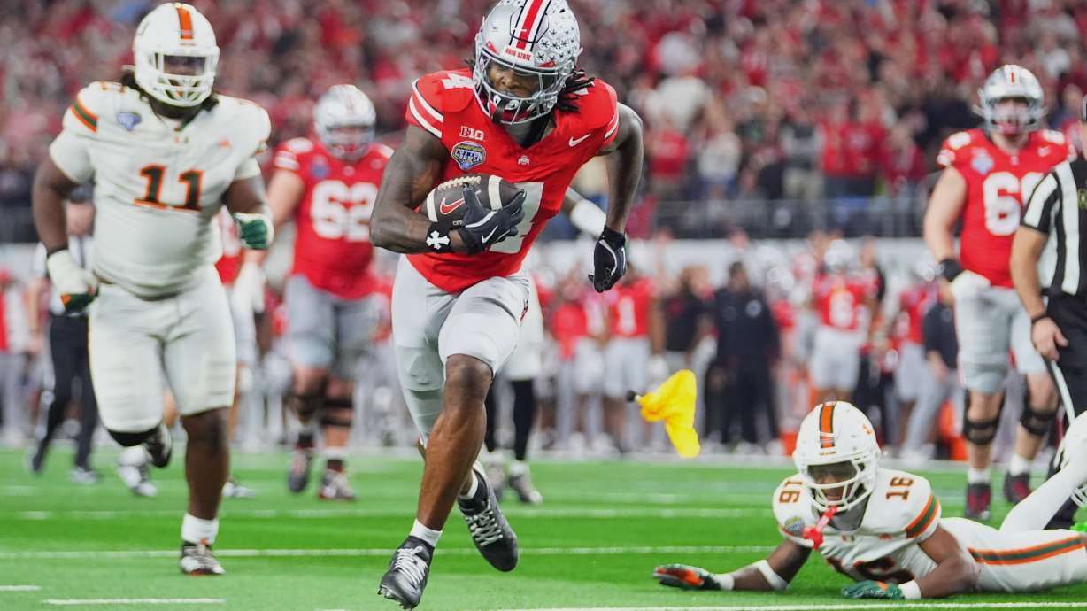 FILE - Ohio State wide receiver Jeremiah Smith, center, gets away from Miami defensive lineman David Blay Jr. (11) and defensive back Ja'Boree Antoine (16) to score a touchdown during the second half of the Cotton Bowl College Football Playoff quarterfinal game Wednesday, Dec. 31, 2025, in Arlington, Texas.