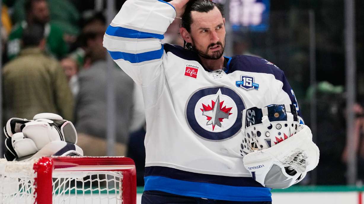 FILE - Winnipeg Jets goaltender Connor Hellebuyck stands by the net during a time out from play against the Dallas Stars in the first period of an NHL hockey game, April 2, 2026, in Dallas.