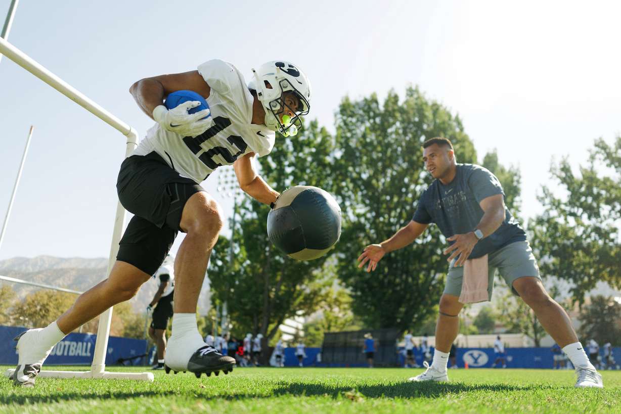 BYU running backs coach Harvey Unga, right, with running back Preston Rex runs drills during training camp, Tuesday, Aug. 25, 2026 in Provo, Utah.