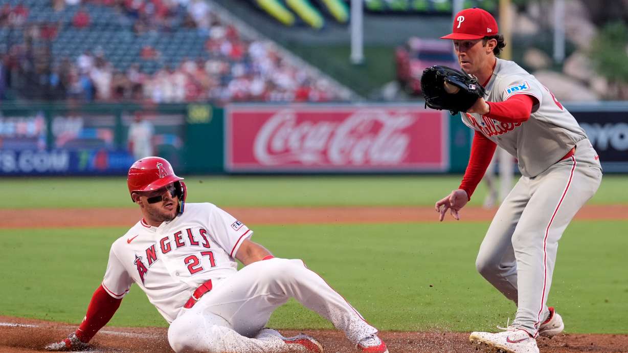 Los Angeles Angels' Mike Trout, left, scores on wild pitch by Philadelphia Phillies starting pitcher Andrew Painter, left, as Painter takes a late throw during the first inning of a baseball game Friday, Aug. 28, 2026, in Anaheim, Calif.