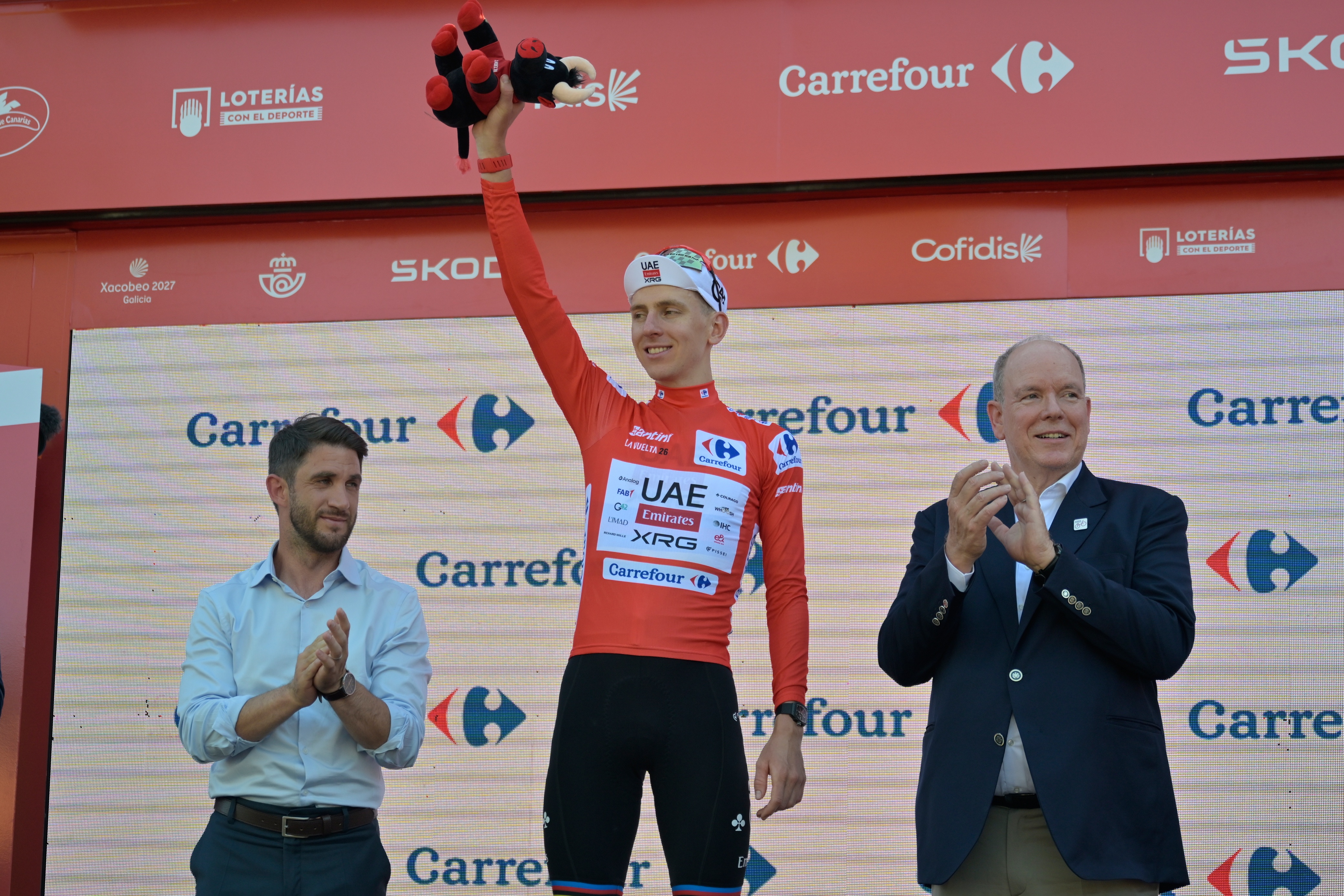 Slovenia's Tadej Pogacar, wearing the overall leader's red jersey celebrates on the podium after the second stage of the La Vuelta cycling race, with start in Monaco and finish in Manosque, France, Sunday, Aug. 23, 2026. 