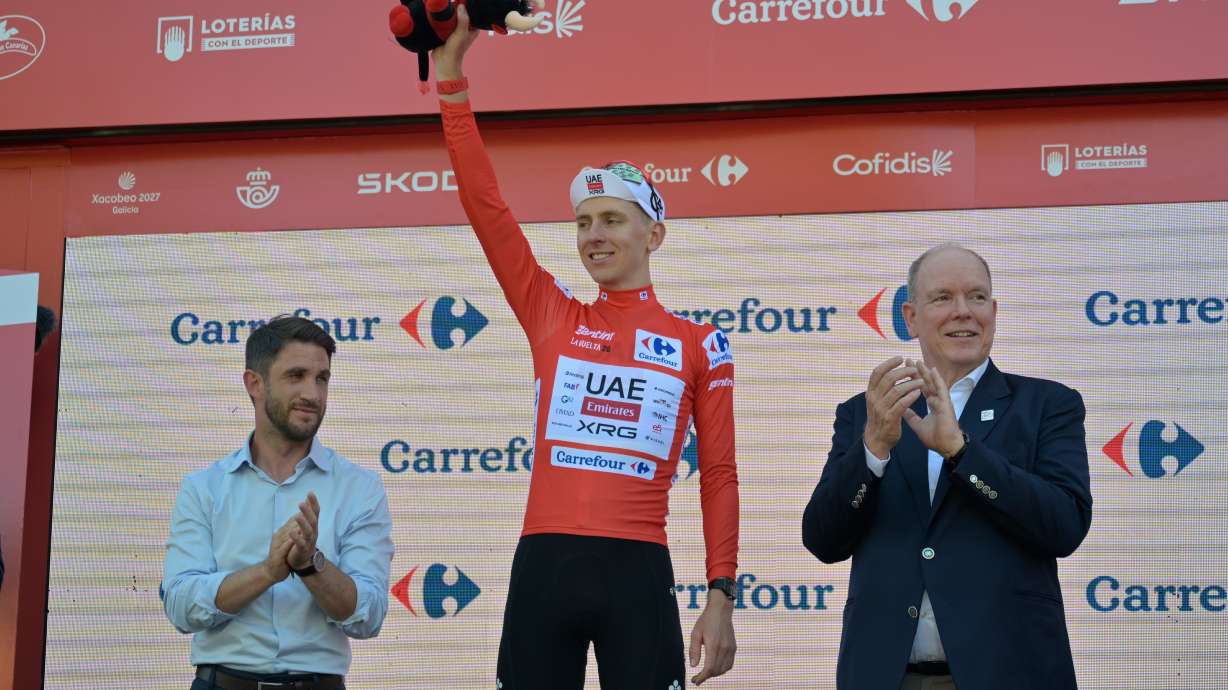 Slovenia's Tadej Pogacar, wearing the overall leader's red jersey celebrates on the podium after the second stage of the La Vuelta cycling race, with start in Monaco and finish in Manosque, France, Sunday, Aug. 23, 2026.