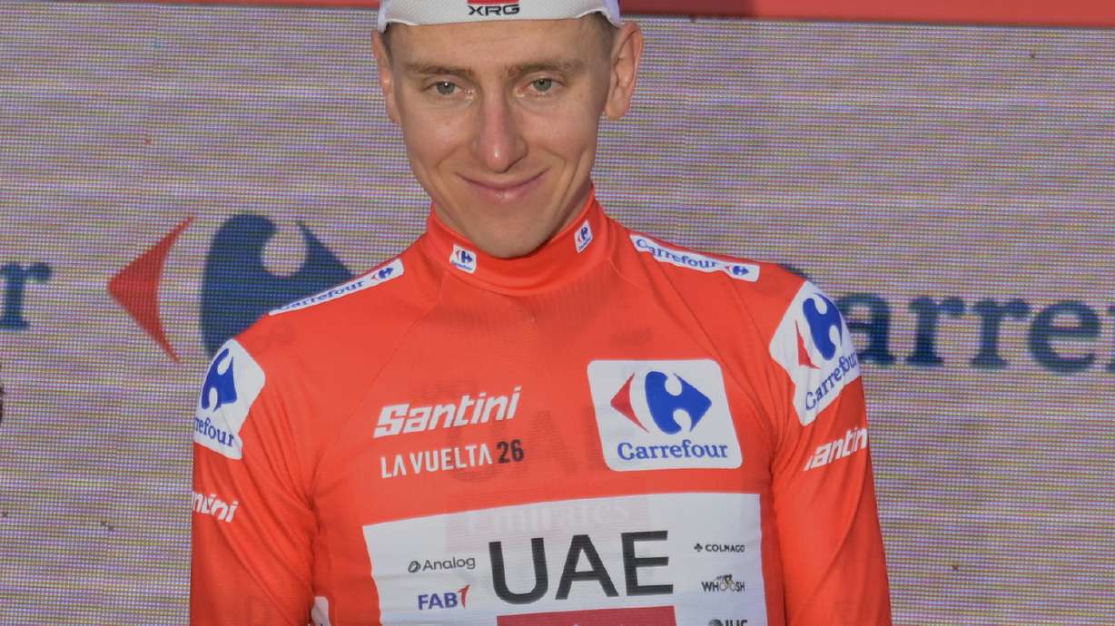 Slovenia's Tadej Pogacar, wearing the overall leader's red jersey celebrates on the podium after the second stage of the La Vuelta cycling race, with start in Monaco and finish in Manosque, France, Sunday, Aug. 23, 2026.