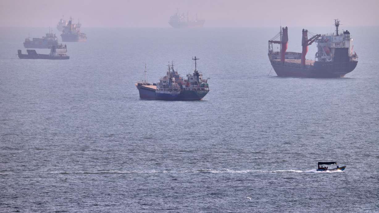 A small boat sails past cargo ships and other commercial vessels anchored in the Strait of Hormuz off Bandar Abbas, Iran, Wednesday, Aug. 5. U.S. forces have struck Iranian rocket launchers on the Strait of Hormuz in the first military action in a month, a U.S. official said Sunday.