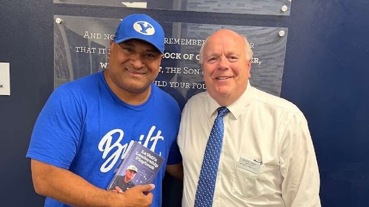 BYU football coach Kalani Sitake poses with a copy of "LaVell's Leadership Playbook" with George Rahlf.