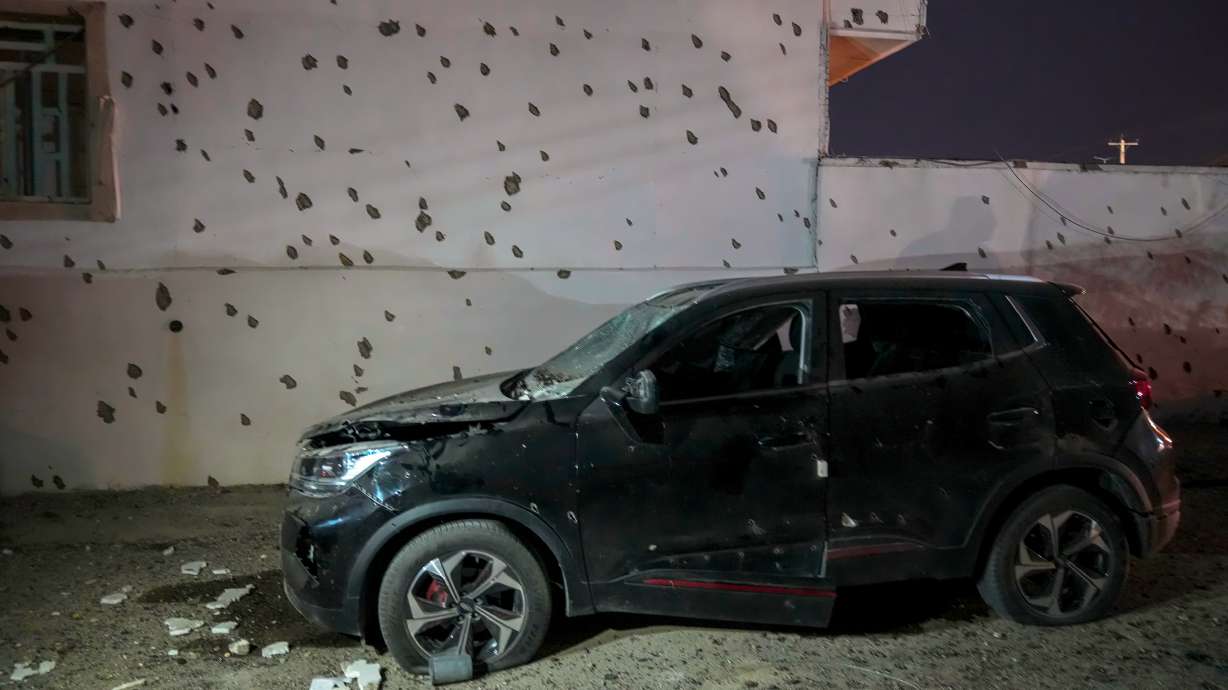 A damaged car sits beside a wall bearing numerous impact marks near the site of a strike in Lamerd, southern Iran, Feb. 28.