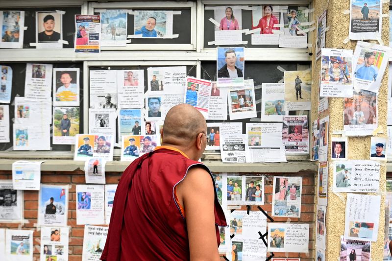 A Buddhist monk looks at photographs of missing and deceased people pasted on wall outside Tribhuvan University Teaching Hospital, following flash floods and a mudslide, in Kathmandu, Nepal, Tuesday. At least 4,000 people remained missing as the death toll crossed 1,000.