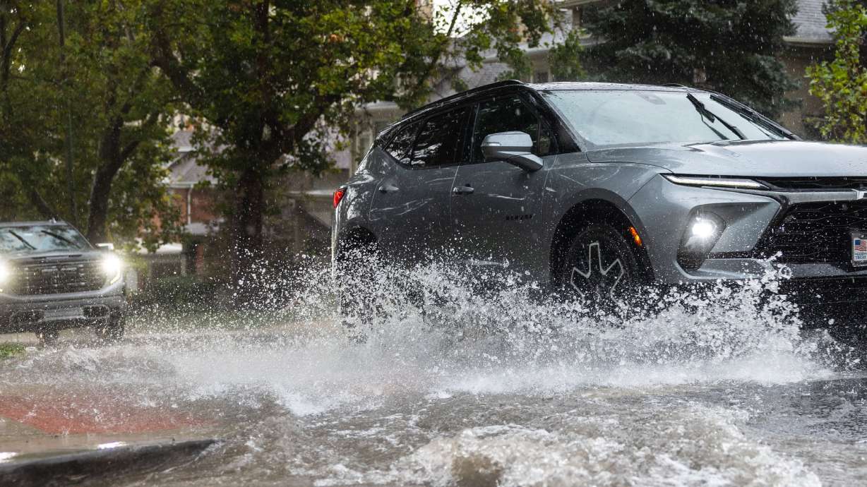 A car splashes a puddle during a heavy rainstorm in Salt Lake City on Aug. 14. Utah has seemingly been caught in an endless water crisis loop of fires, floods and drought.