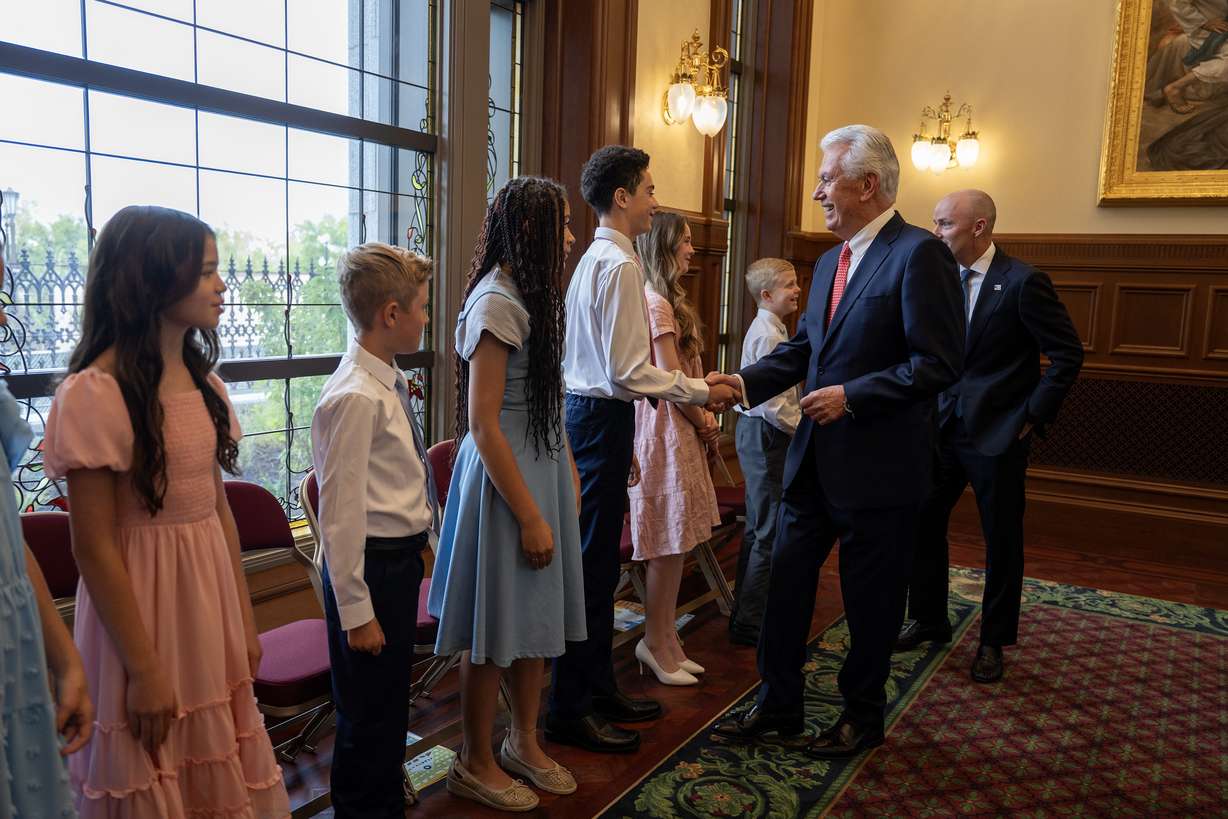 President Dieter F. Uchtdorf, acting president of the Quorum of the Twelve Apostles of The Church of Jesus Christ of Latter-day Saints, and Gov. Spencer Cox shake hands with members of a children’s choir prior to the announcement of the Salt Lake Temple celebration theme on Temple Square in Salt Lake City on Tuesday.