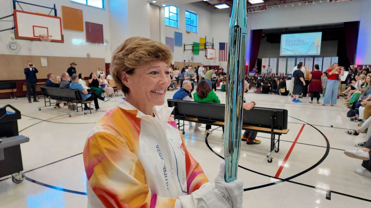 Amy Garf, who was a torchbearer in the Milan-Cortina games, leads students in a march around the assembly hall inside Backman Elementary School.